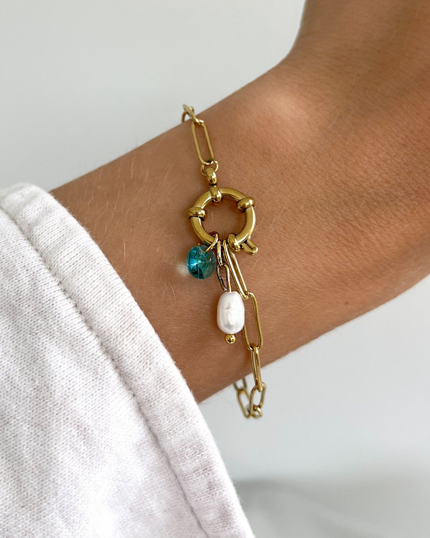 Wasserfester Edelstahl Anhänger mit Süßwasserperle an goldenem Armband.