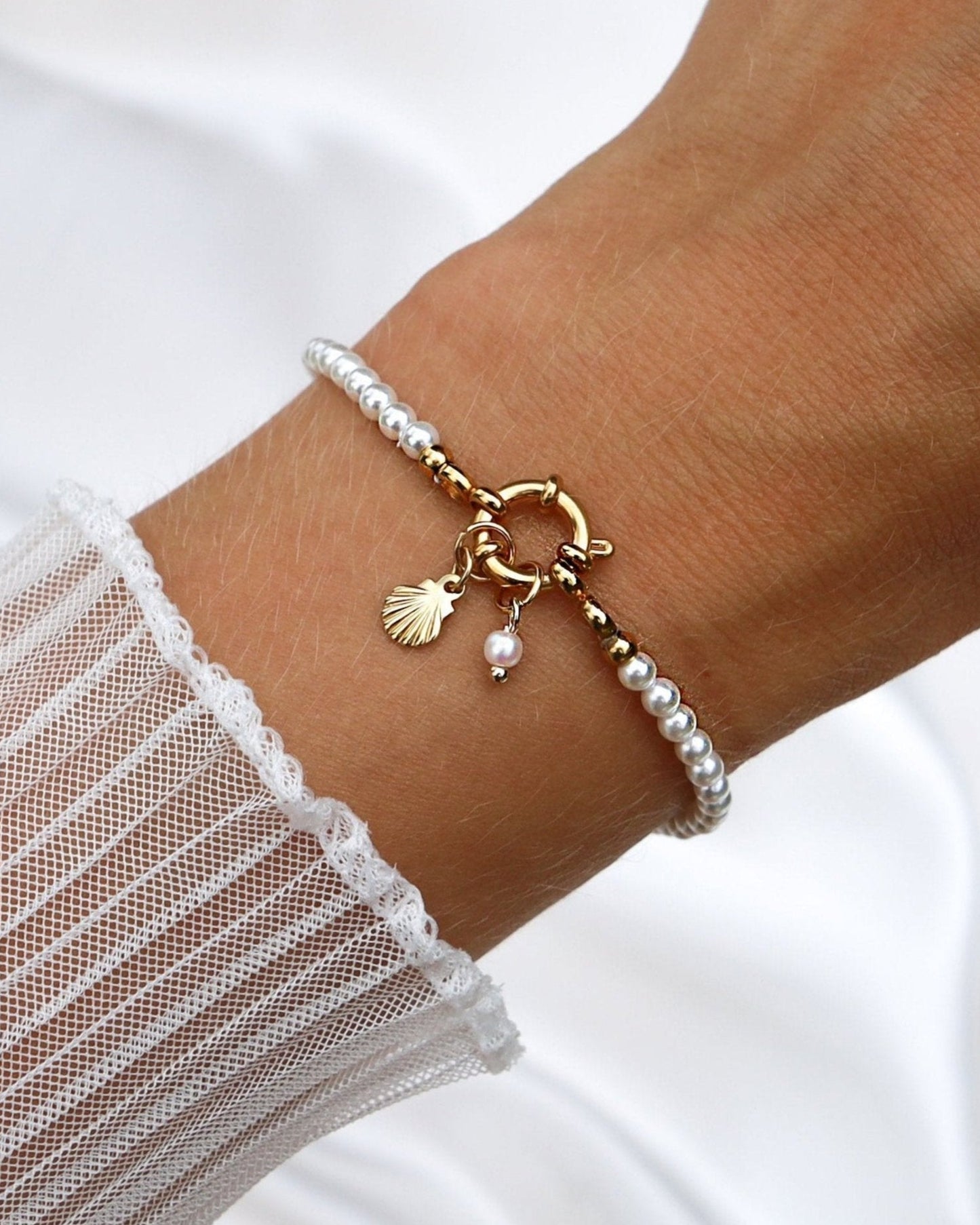 Wasserfester Edelstahl Charm in Muschelform an einem Perlenarmband.