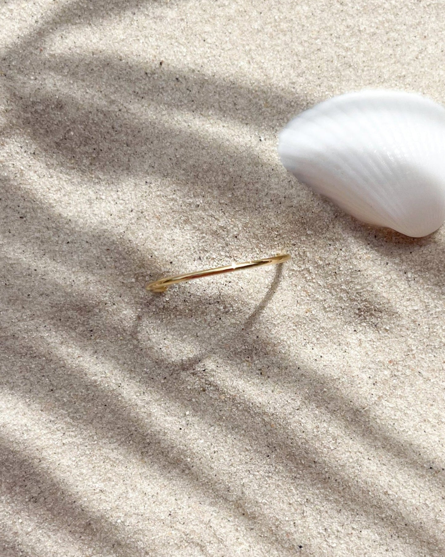 Schlichter, dezenter, verstellbarer Edelstahl Ring im Sand.