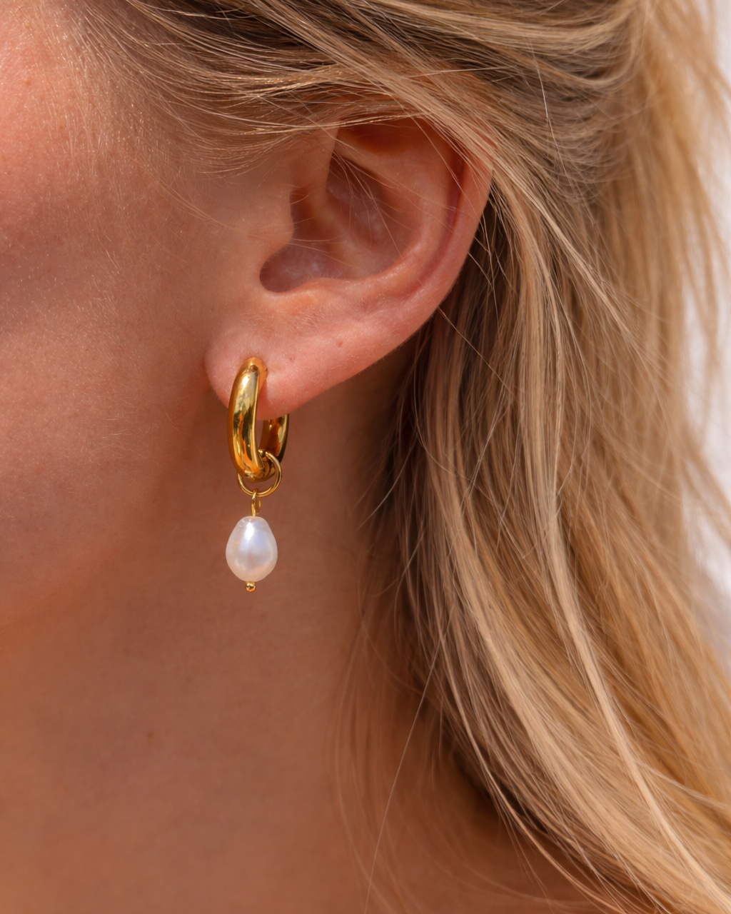 Gold Huggie Creolen mit Perlenanhänger bei natürlichem Sonnenlicht