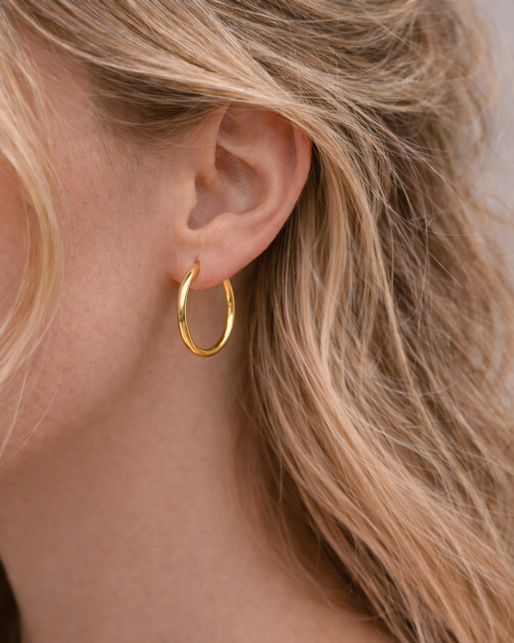 Goldene Creolen 2,5 cm aus Edelstahl an Modell.