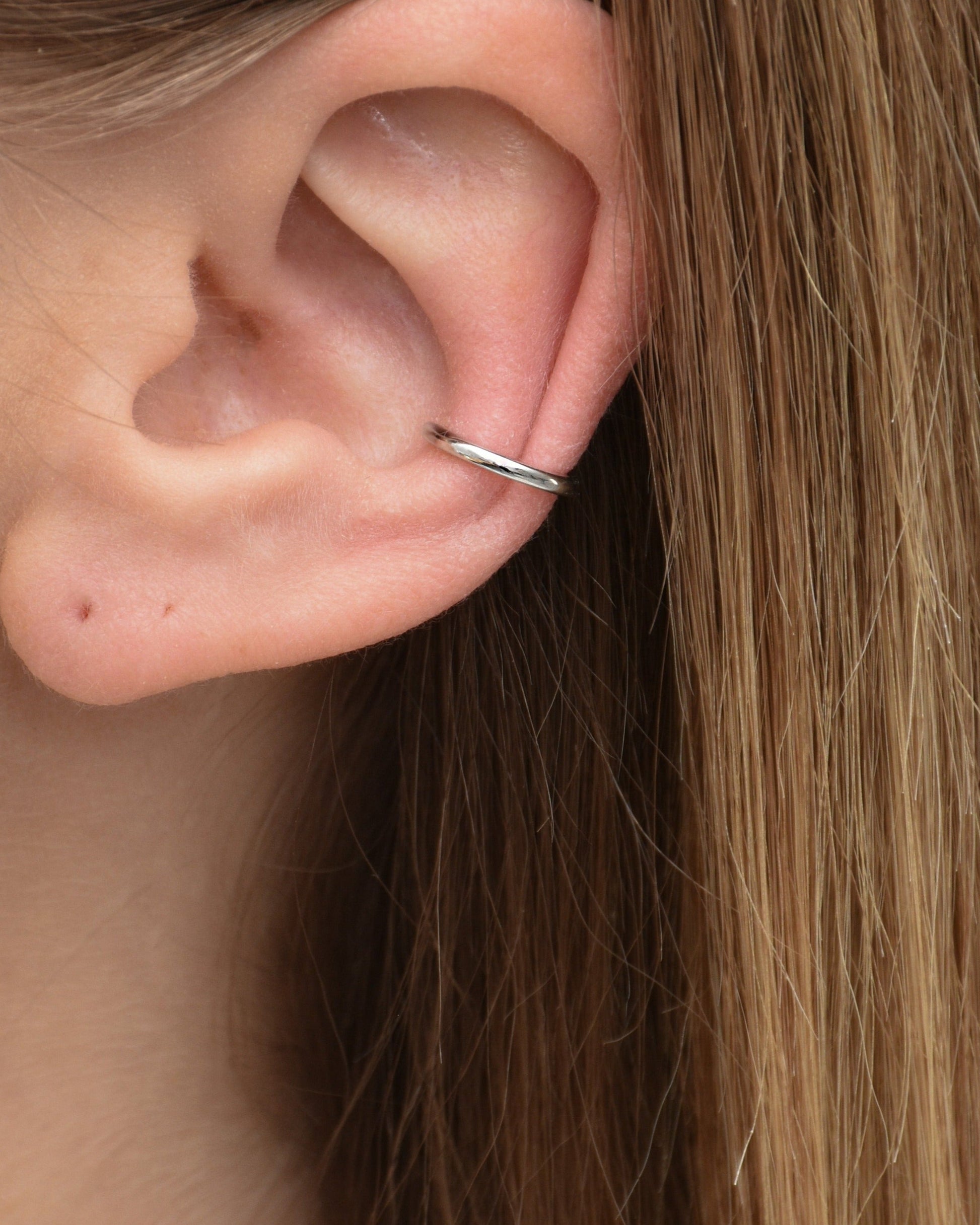 Feiner Edelstahl Earcuff in silber, getragen am Ohr.
