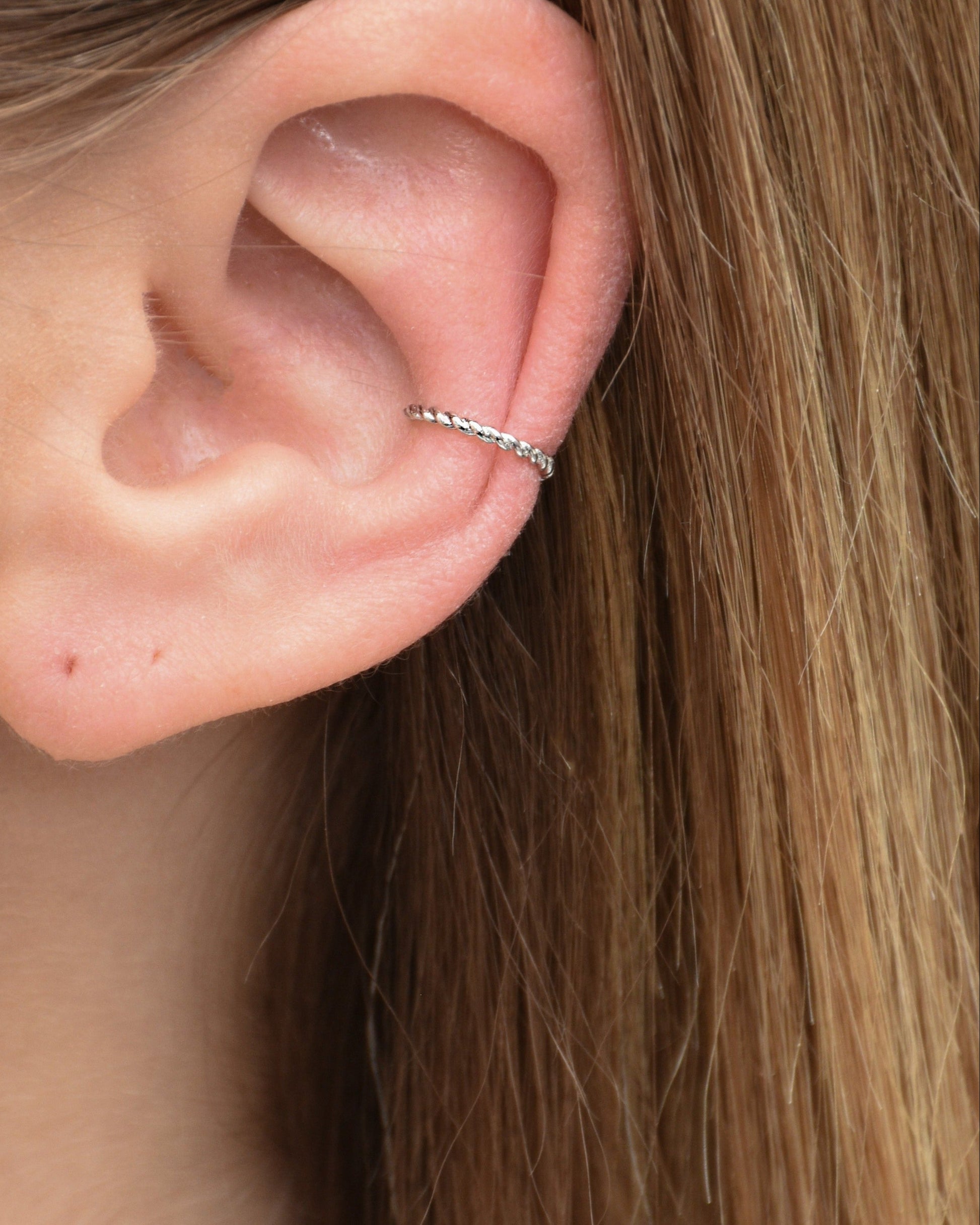 Feiner gedrehter Edelstahl Earcuff in silber getragen am Ohr.