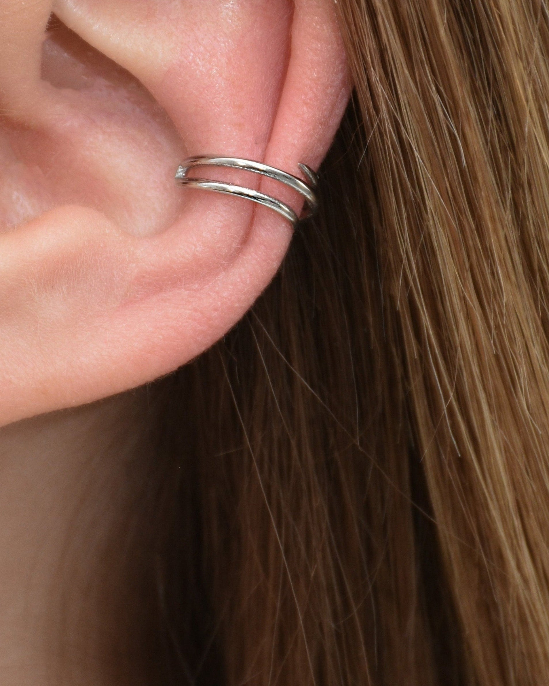 Edelstahl Earcuff mit besonderem Design in silber getragen am Ohr.