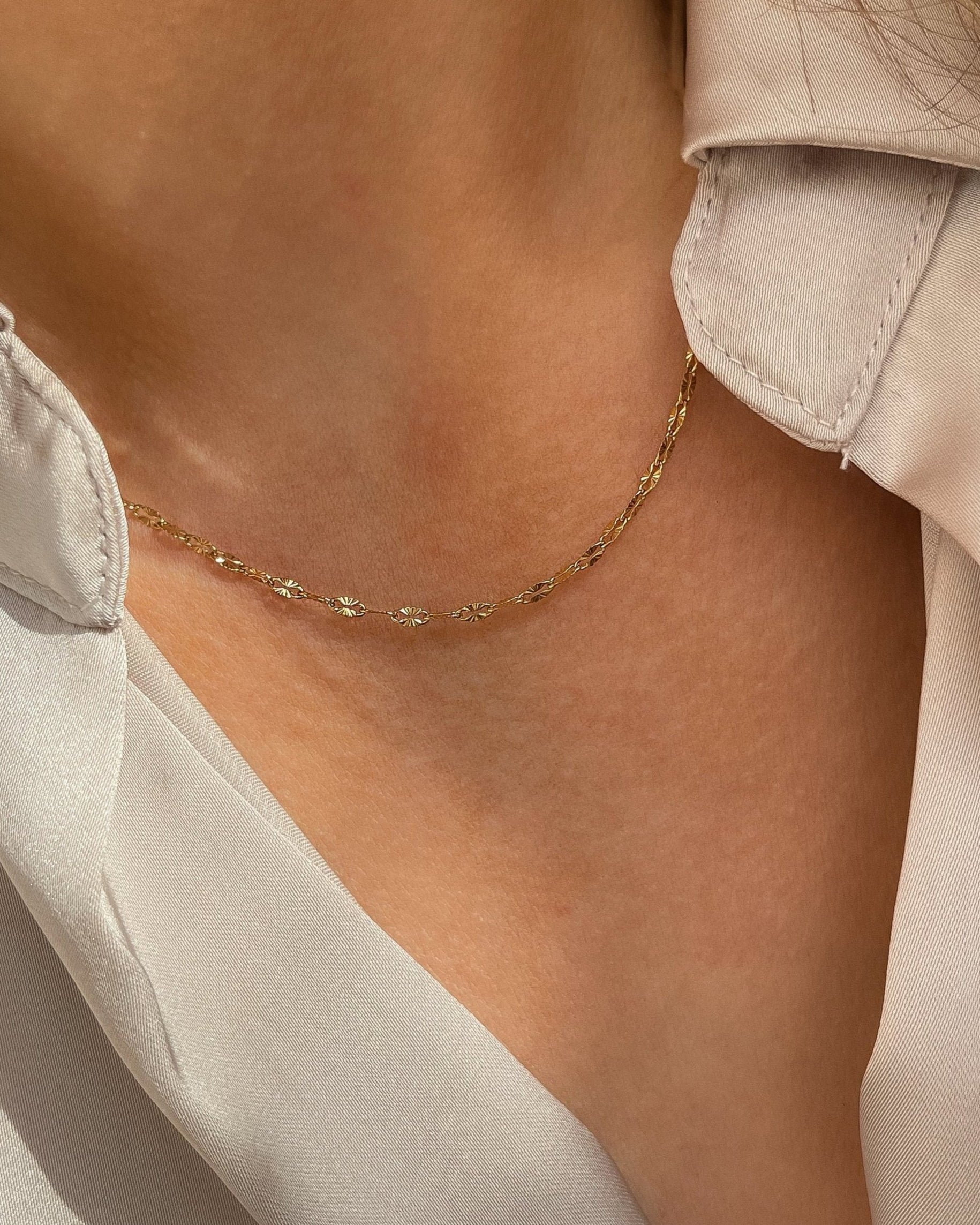 Filigrane vergoldete Edelstahlkette mit zarten, strukturierten Gliedern. Wasserfest und hypoallergen, getragen mit beigefarbener Bluse.