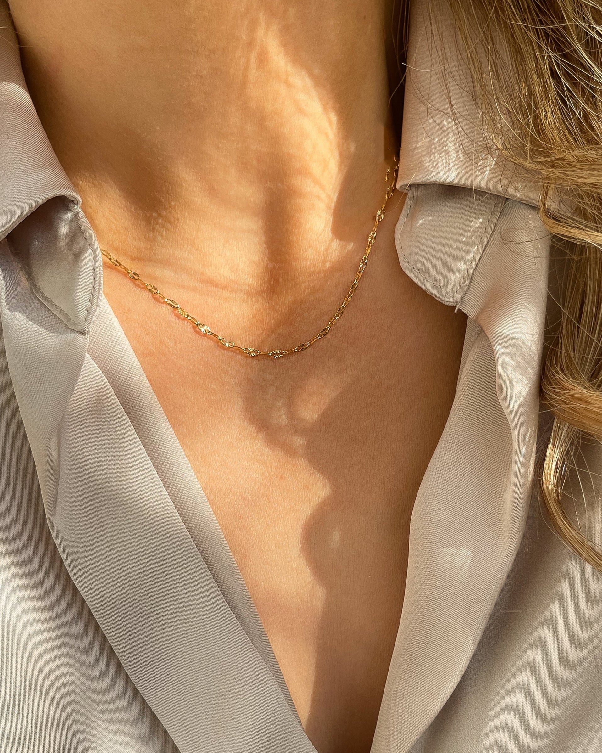 Filigrane vergoldete Edelstahlkette mit zarten, strukturierten Gliedern. Wasserfest und hypoallergen, getragen mit beigefarbener Bluse.