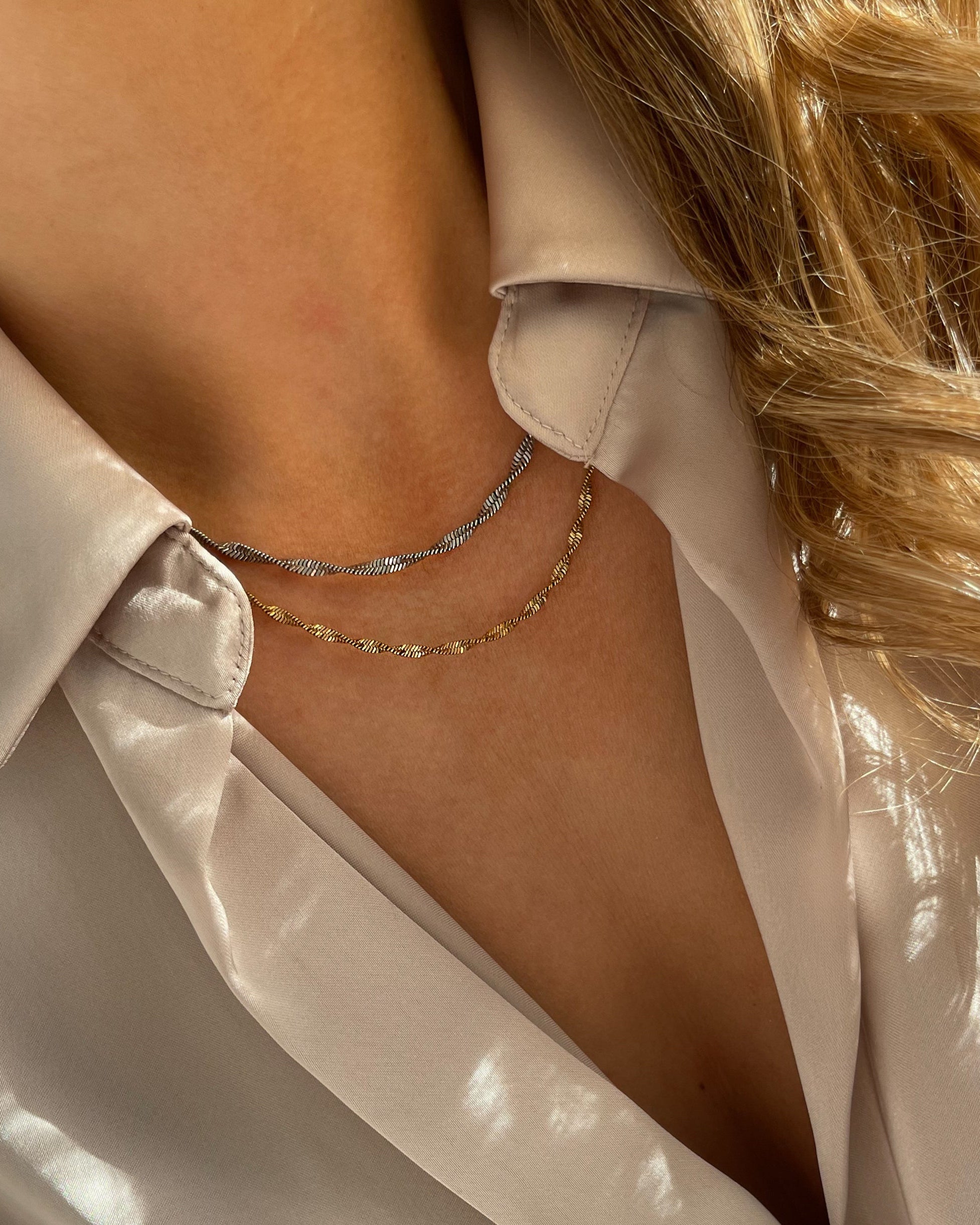 In sich gedrehte Edelstahl Kette mit 18k Vergoldung. Getragen mit einer beigefarbenen Bluse. Wasserfest und hypoallergen.