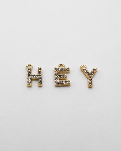 Goldene Buchstaben Anhänger mit Zirkonia Steinen.