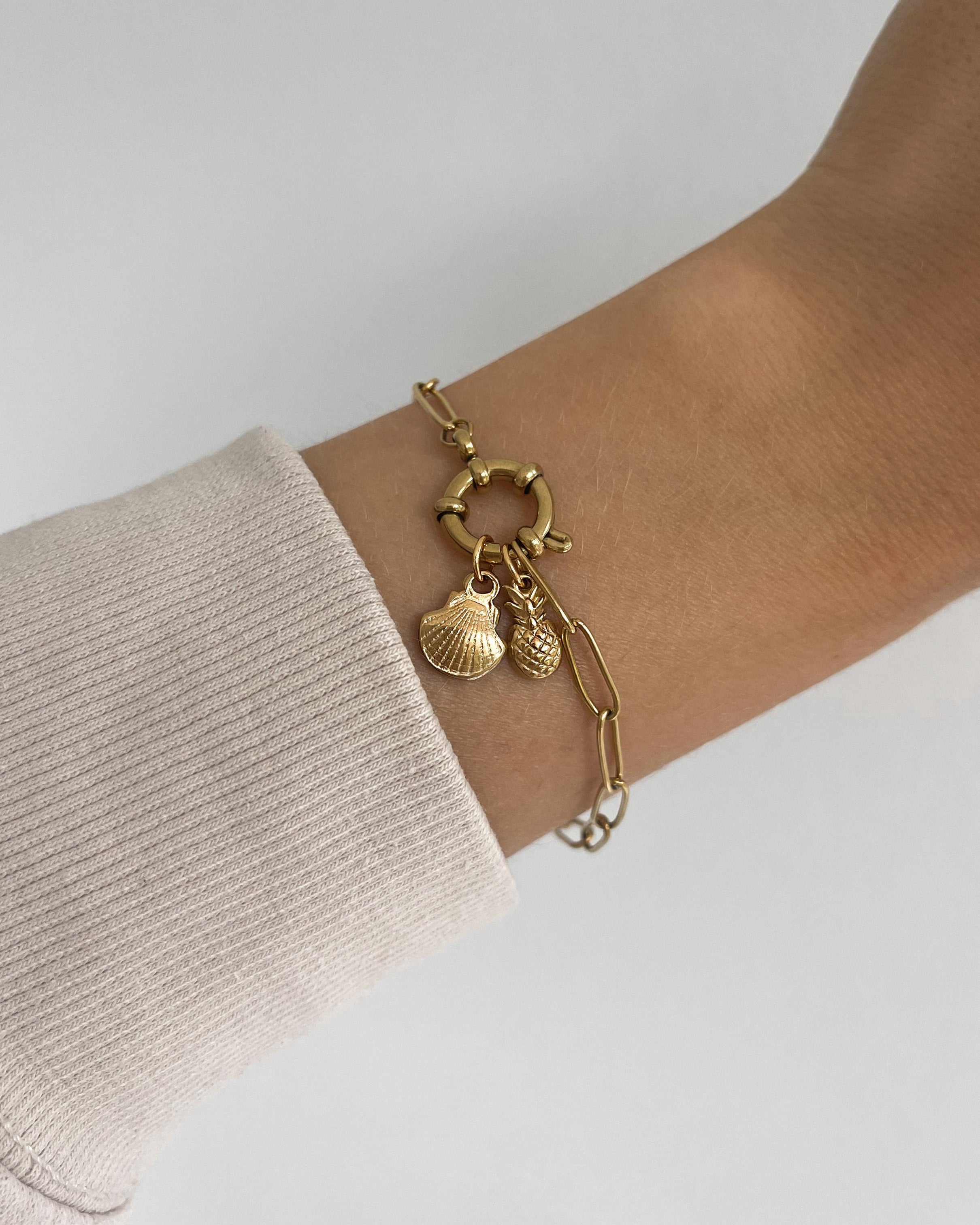Edelstahl Charm in Muschelform an goldenem Armband. Wasserfest und hypoallergen.