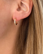 Wasserfeste Edelstahl Hoops mit Zirkonia Steinen besetzt in gold, getragen am Ohr.