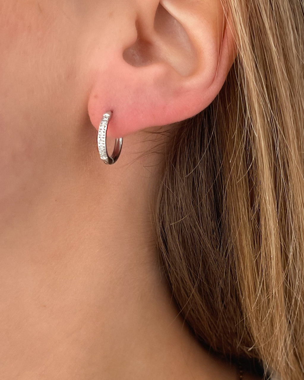 Wasserfeste Edelstahl Hoops mit Zirkonia Steinen besetzt in silber, getragen am Ohr.