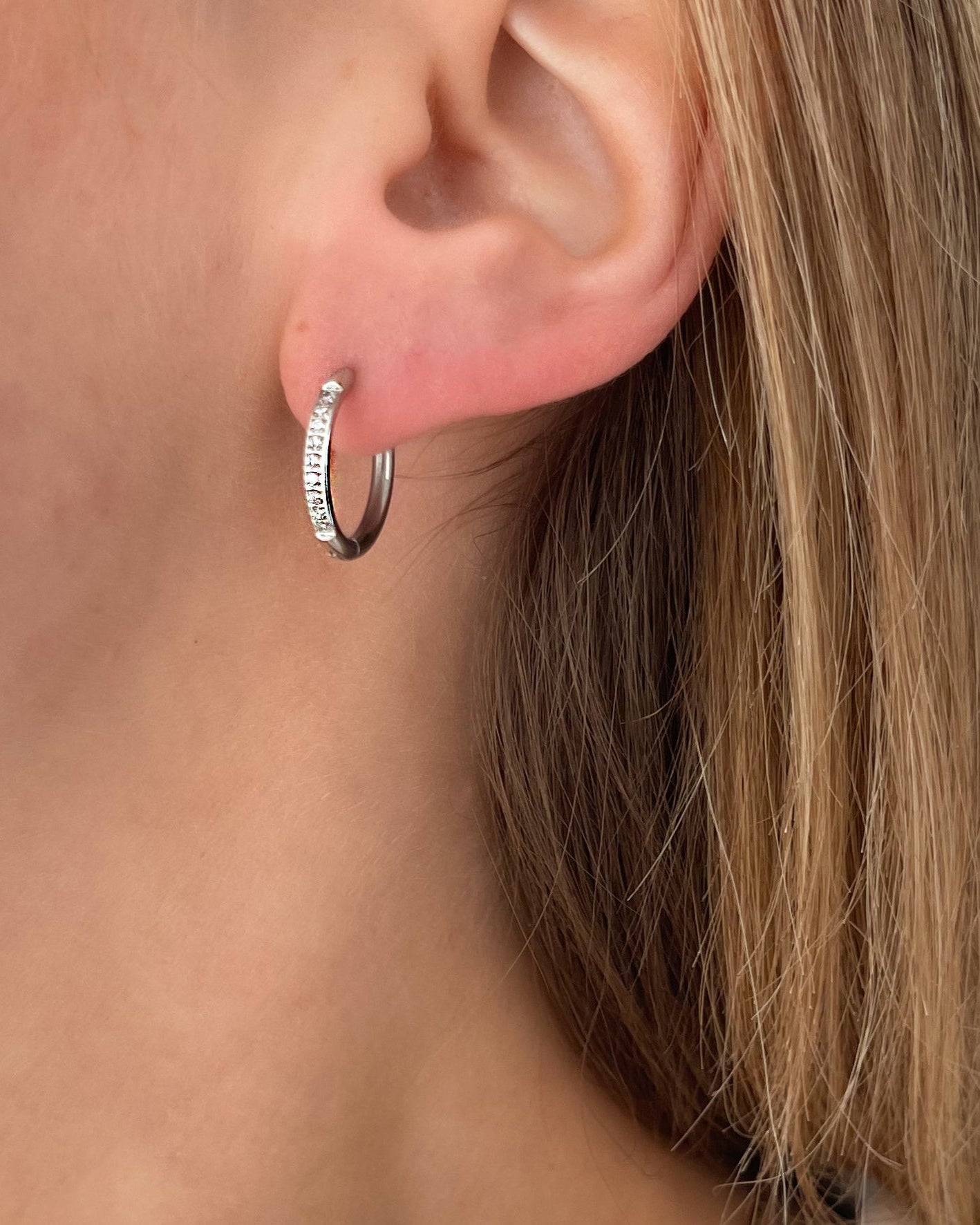 Wasserfeste Edelstahl Hoops mit Zirkonia Steinen besetzt in silber, getragen am Ohr.