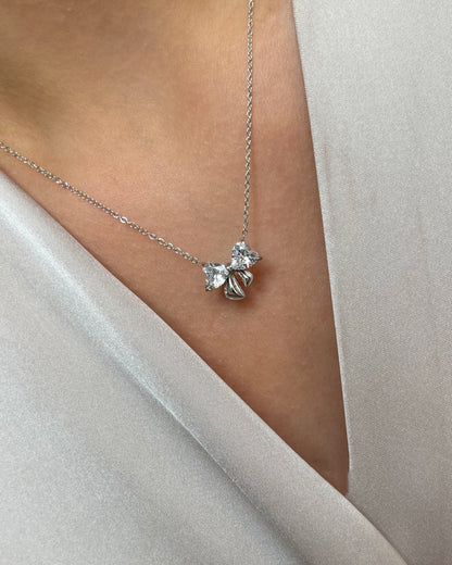 Edelstahl Halskette mit Schleifen Design in silber mit Herzförmigen Zirkonia Steinen. Wasserfest und hypoallergen., getragen mit einer cremefarbenen Bluse.
