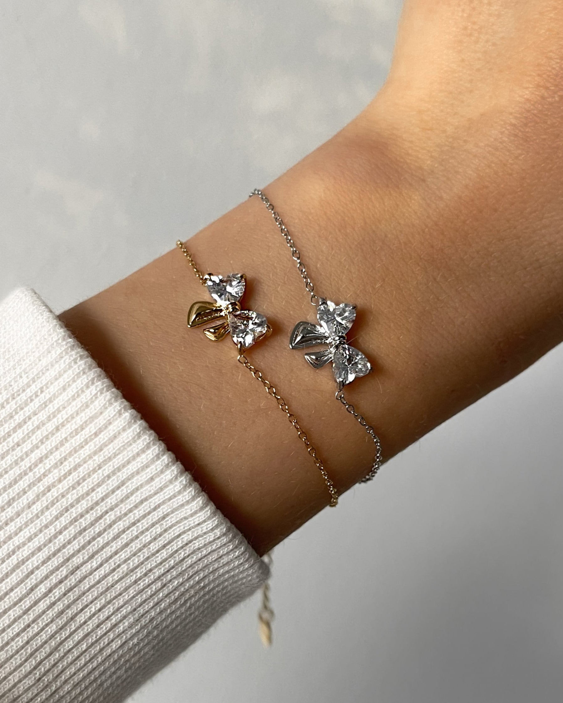 Feines Edelstahl Armband mit Schleifen Detail aus Zirkonia Steinen, getragen am Arm in gold und silber.