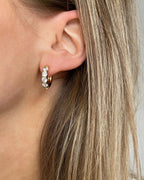 Wasserfeste Edelstahl Hoops mit Zirkonia Steinen besetzt in gold, getragen am Ohr.
