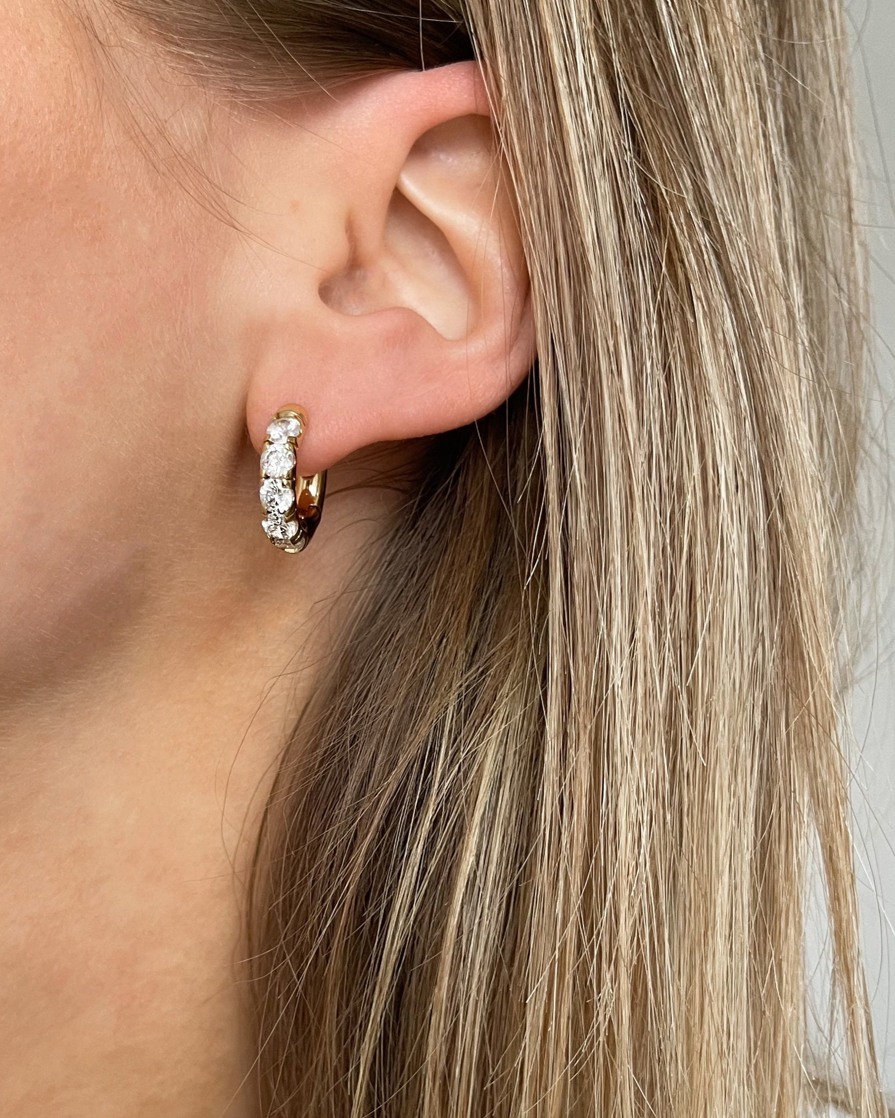 Wasserfeste Edelstahl Hoops mit Zirkonia Steinen besetzt in gold, getragen am Ohr.