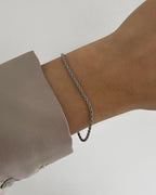 Feines, wasserfestes Edelstahl Armband mit gedrehtem Design, getragen am Handgelenk in silber.
