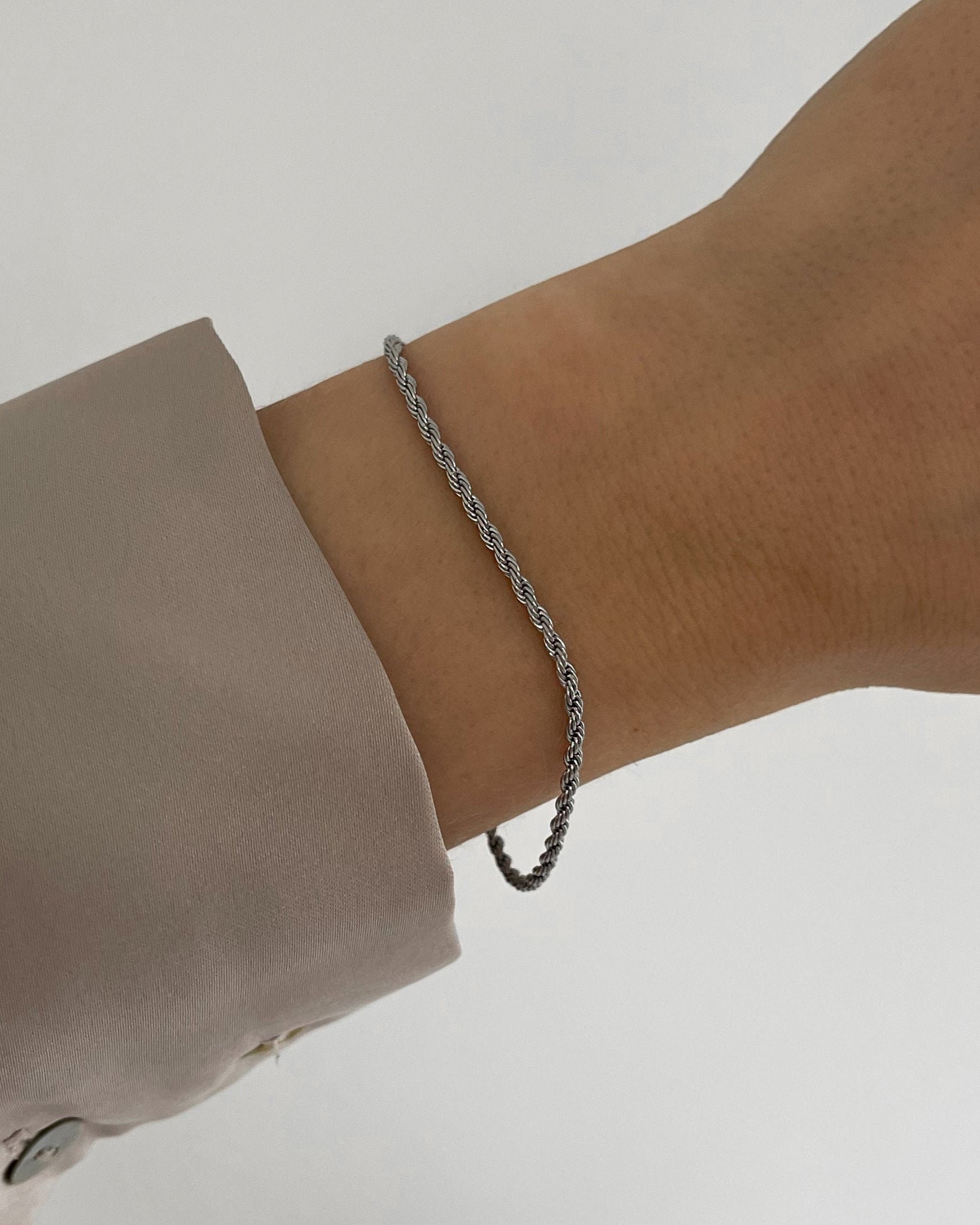 Feines, wasserfestes Edelstahl Armband mit gedrehtem Design, getragen am Handgelenk in silber.