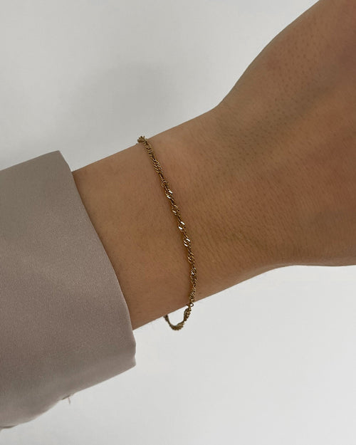 Feines, wasserfestes Edelstahl Armband mit gedrehtem Design, getragen am Handgelenk.
