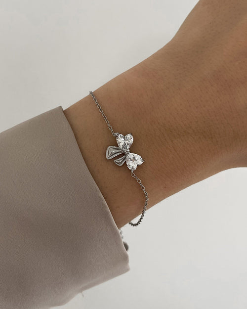 Feines Edelstahl Armband mit Schleifen Detail aus Zirkonia Steinen, getragen am Arm in silber.