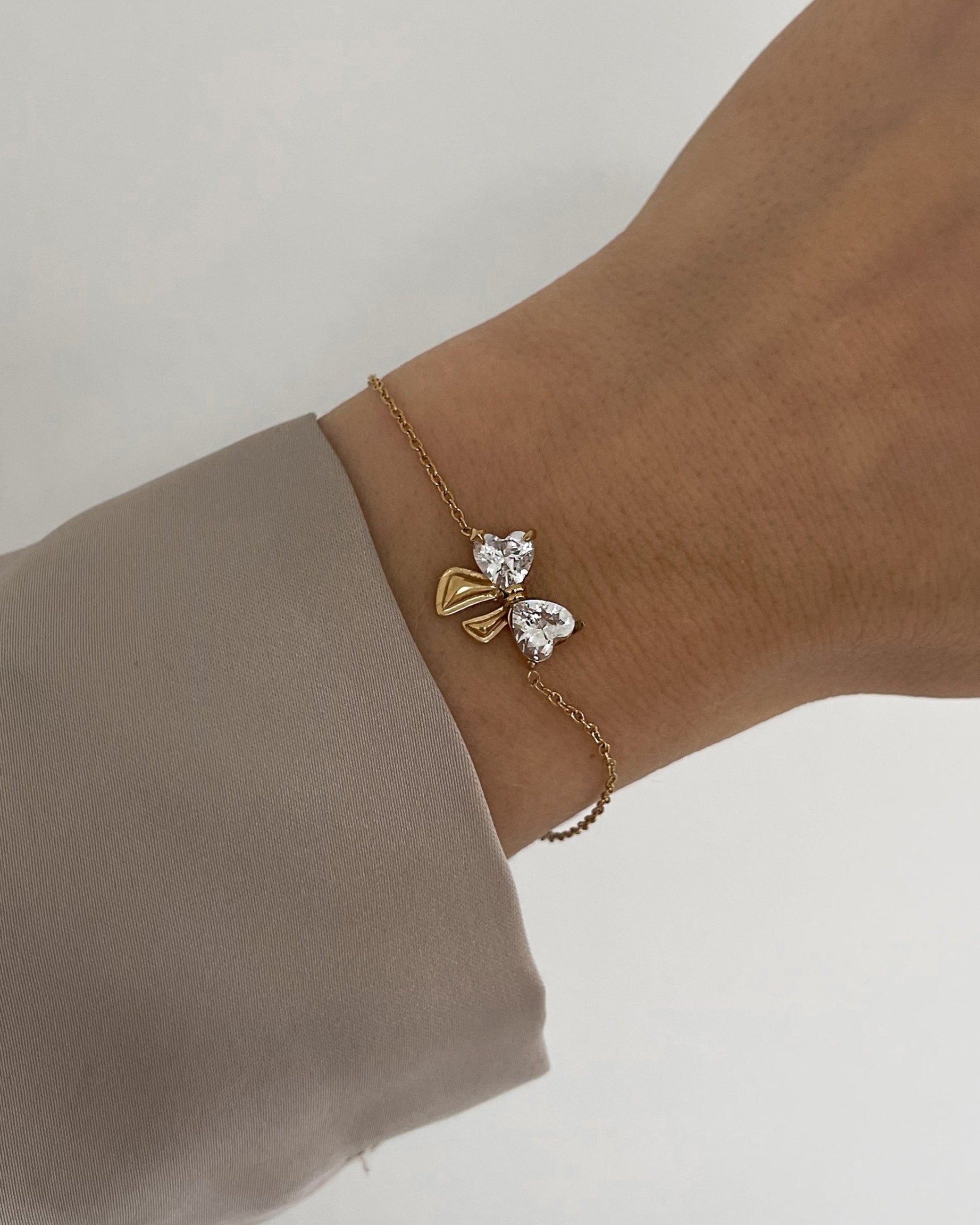 Feines Edelstahl Armband mit Schleifen Detail aus Zirkonia Steinen, getragen am Arm in gold.