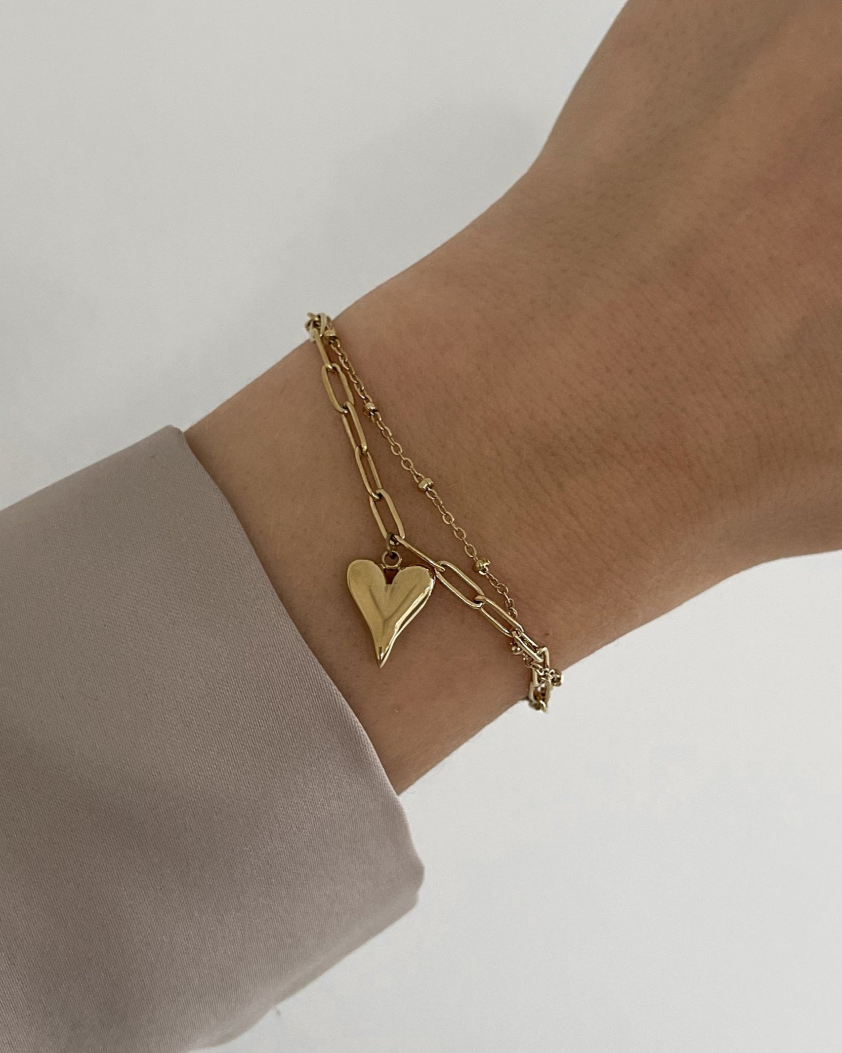 Wasserfestes, doppellagiges Edelstahl Armband mit Herz Anhänger in gold, getragen am Arm.
