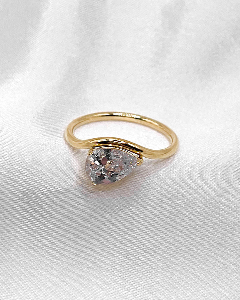 Wasserfester, goldener Edelstahl Ring geschwungen mit einem Tropfen Zirkonia, getragen am Finger.