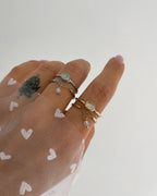 Doppellagiger Ring mit schimmerndem Detail und Kettendesign, getragen am Finger.