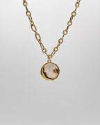 Grobe Halskette mit einem Anhänger aus schimmernder Muschelperle und Details in Mond und Sternform.