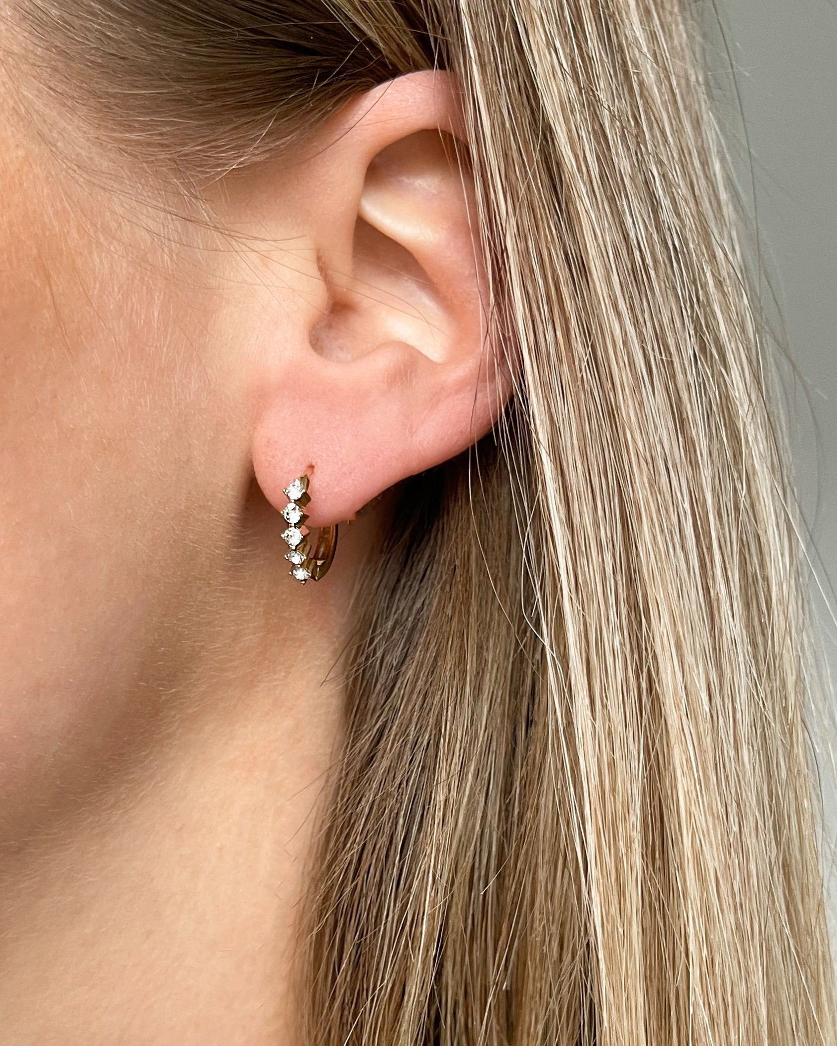 Funkelnde Ohrringe mit fünf Zirkonia Steinen in gold, getragen.