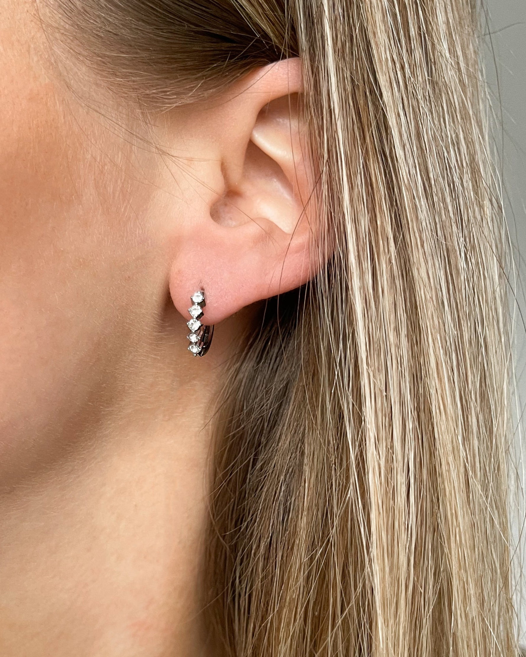 Funkelnde Ohrringe mit fünf Zirkonia Steinen in silber, getragen.