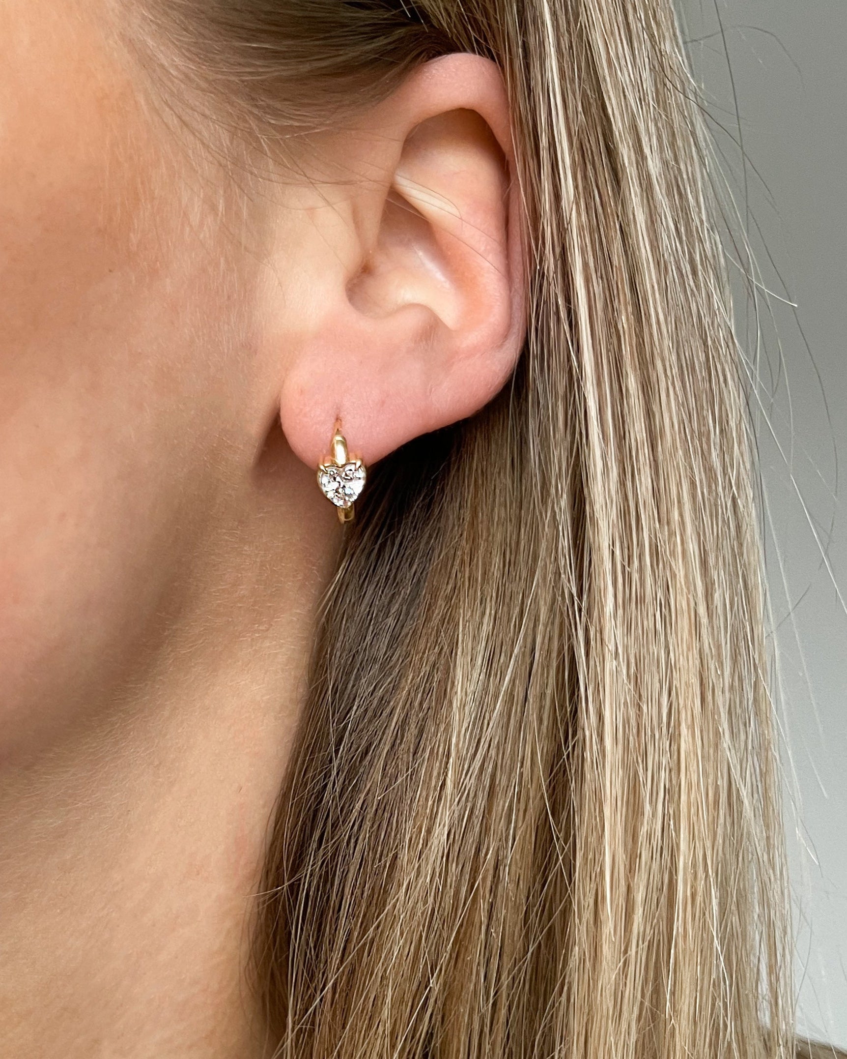 Süße Ohrringe mit verspieltem Herz-Design aus Zirkonia Steinen, in gold, getragen.