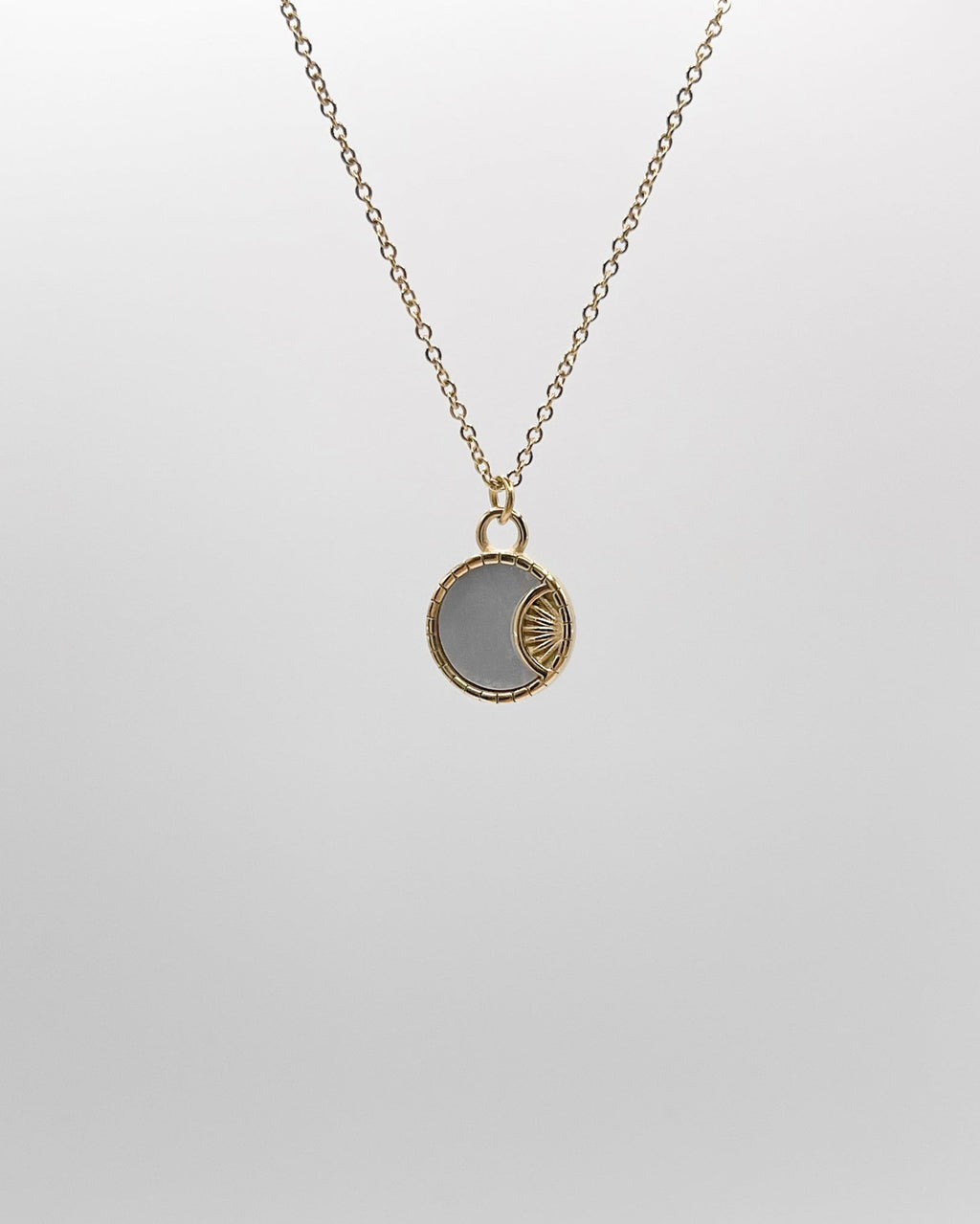 Goldene Halskette mit rundem schimmernden Plättchen.