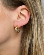Goldene Ohrstecker in gedrehtem Design, getragen am Ohr.