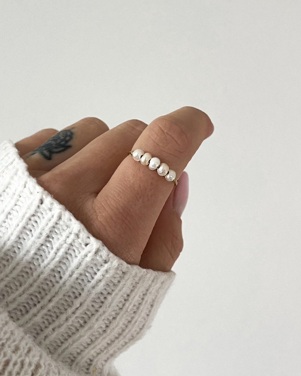 Edelstahlring mit kleinen Süßwasserperlen besetzt, getragen am Finger.