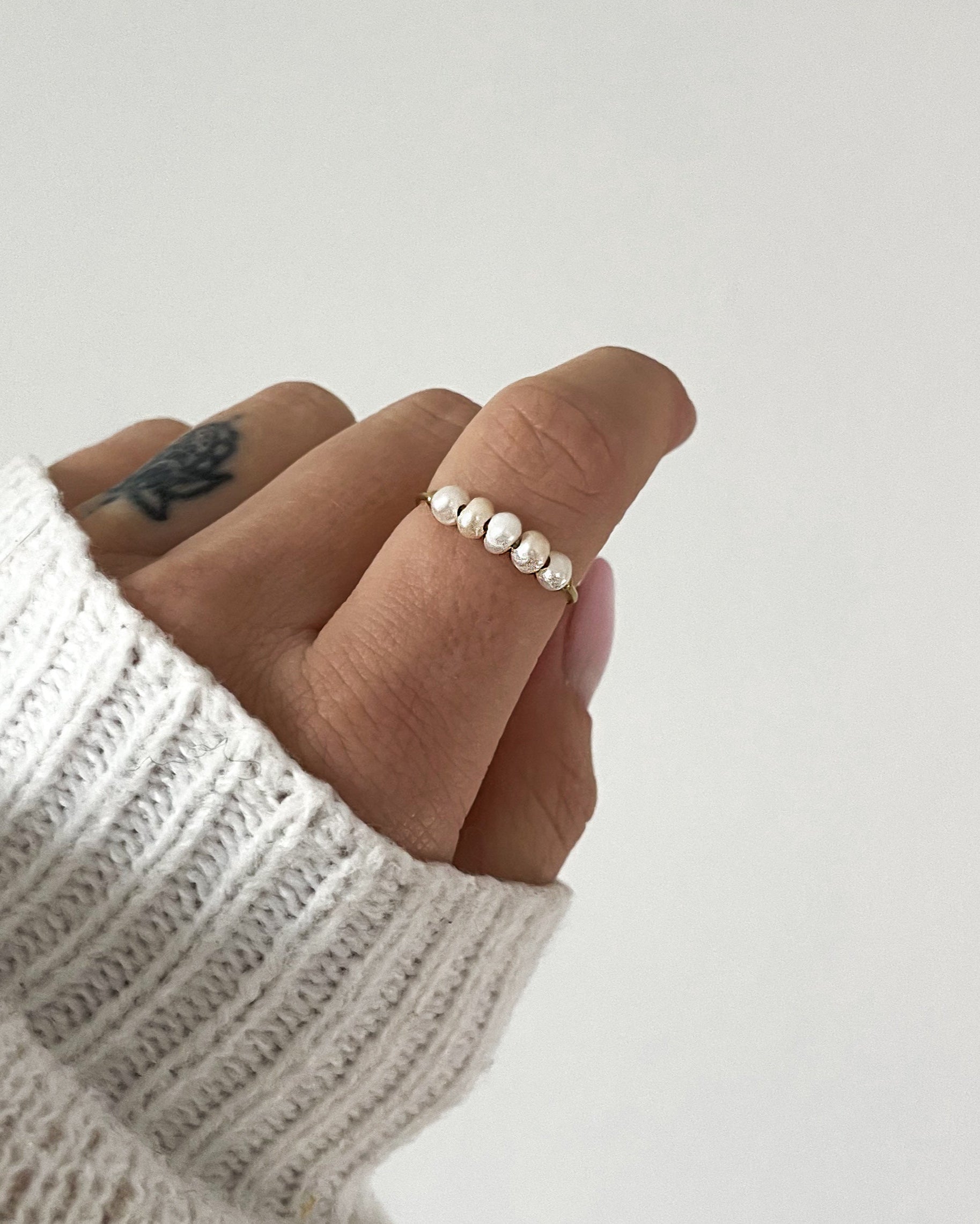 Edelstahlring mit kleinen Süßwasserperlen besetzt, getragen am Finger.