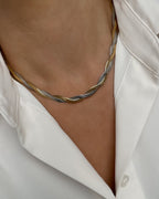 Vergoldete Edelstahl Kette in BiColor mit gedrehtem Schlangen Design, getragen mit einer weißer Bluse. 