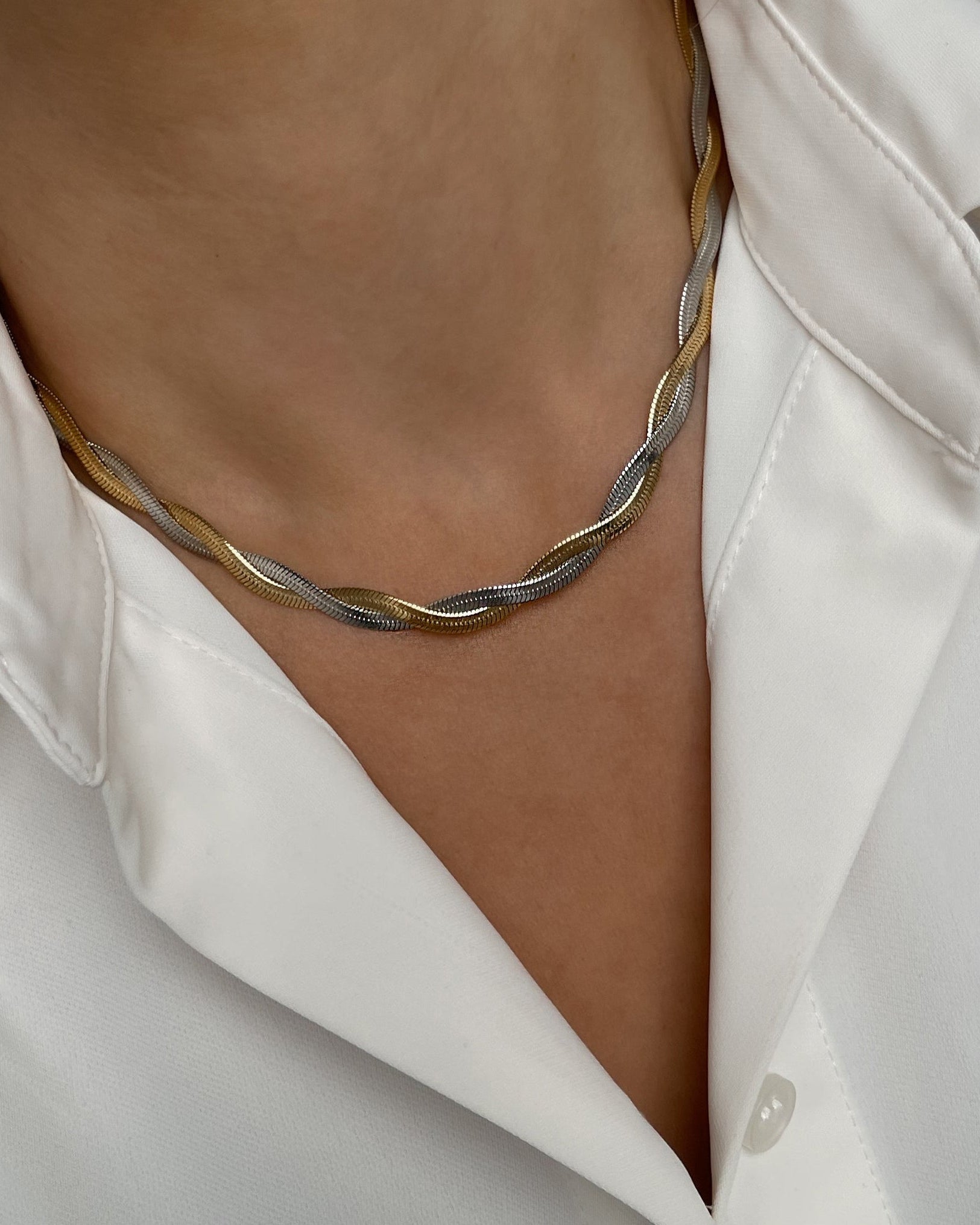 Vergoldete Edelstahl Kette in BiColor mit gedrehtem Schlangen Design, getragen mit einer weißer Bluse. 