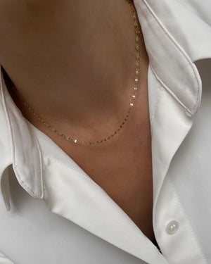 Filigrane vergoldete Edelstahlkette mit zarten, strukturierten Gliedern, getragen mit weißer Bluse.