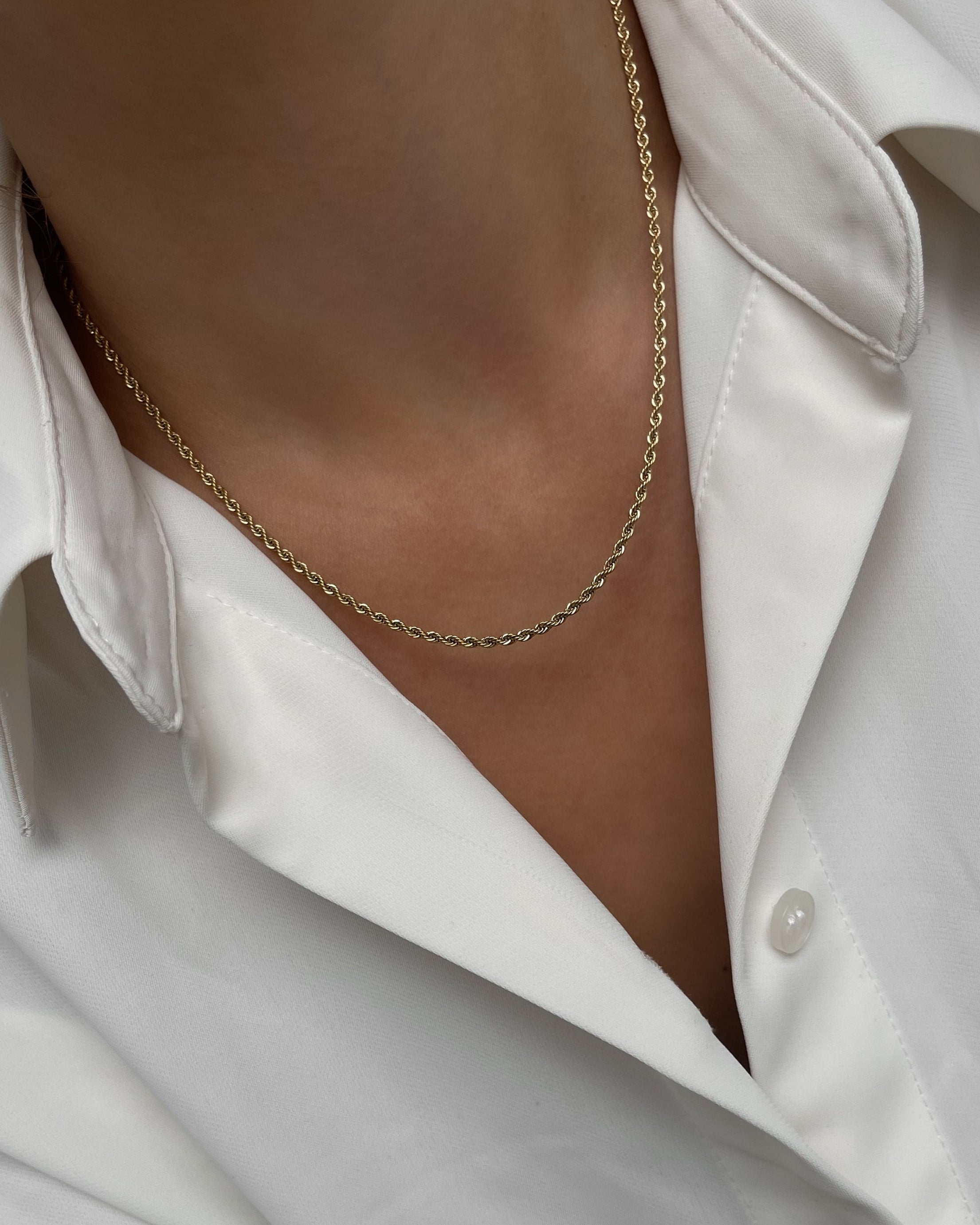 Gedrehte Edelstahl Kette in gold, getragen mit weißer Bluse. 