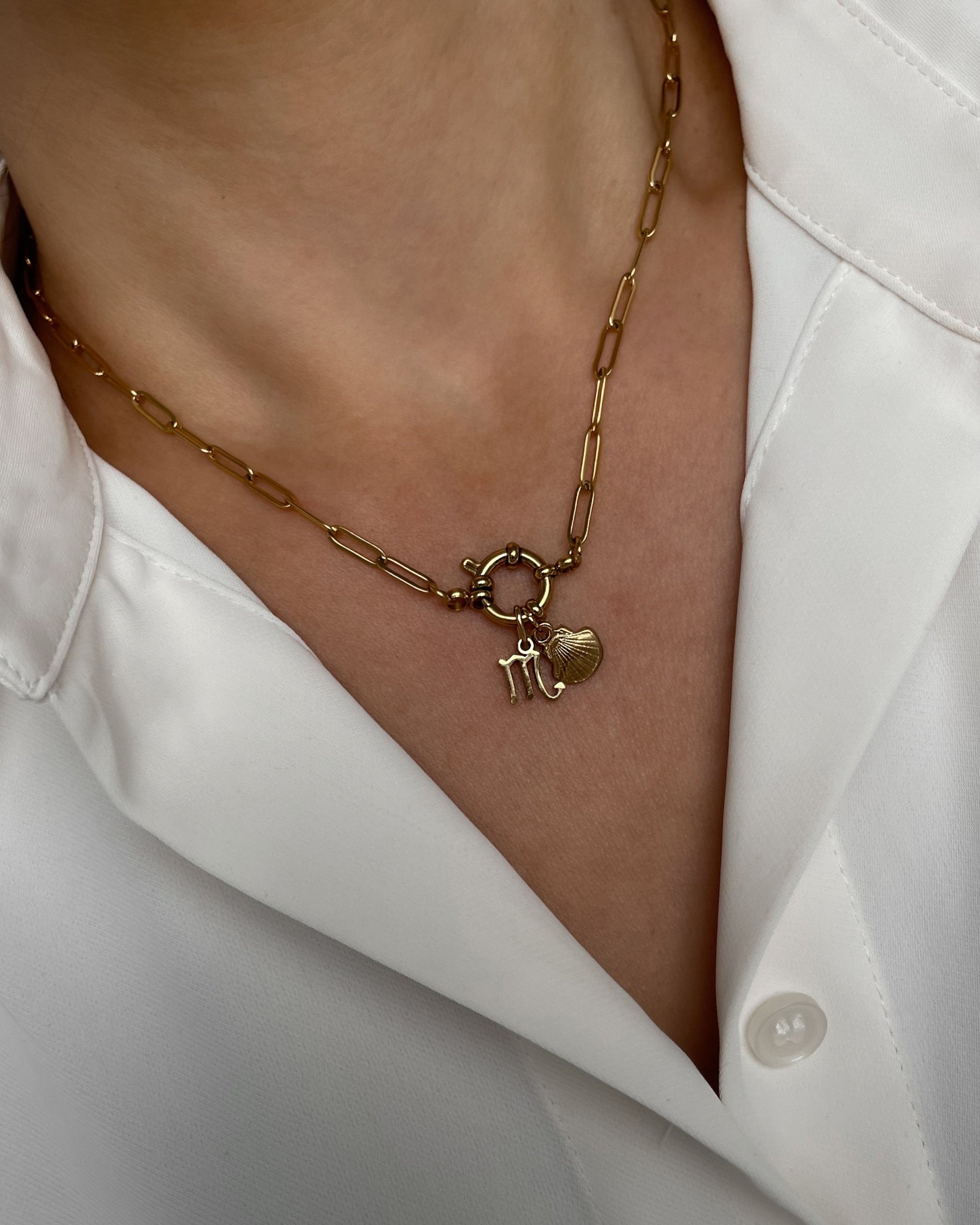 Goldene Charm Halskette mit zwei Anhängern, getragen mit einer weißen Bluse.