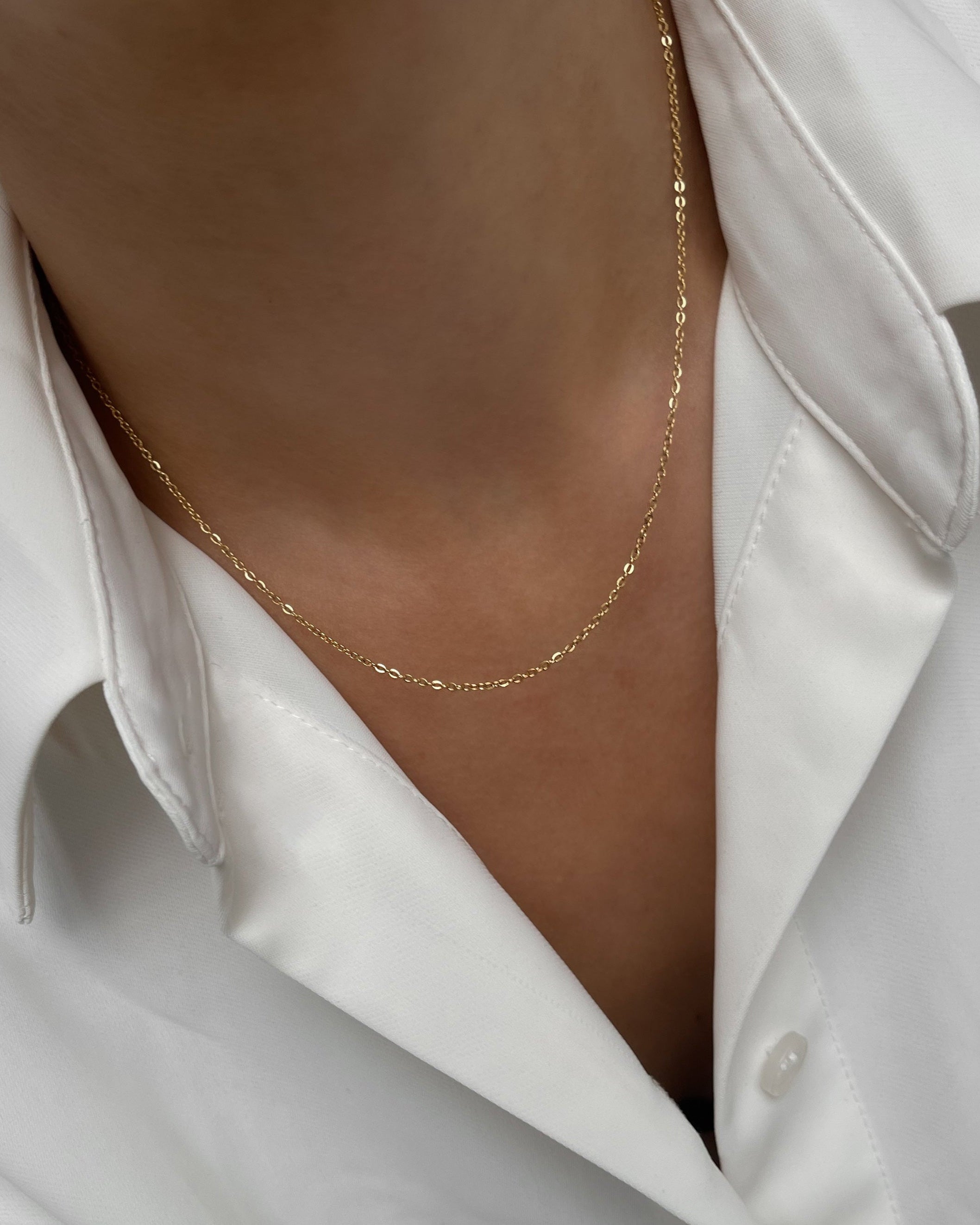 Simple, filigrane Edelstahl Halskette, getragen mit weißer Bluse. Wasserfest und hypoallergen.