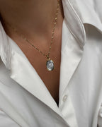 Vergoldete Edelstahlkette mit Muschelperlmutt Design, elegant, getragen mit weißer Bluse. 