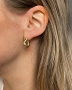Goldene Ohrstecker in gedrehtem Design, getragen am Ohr.