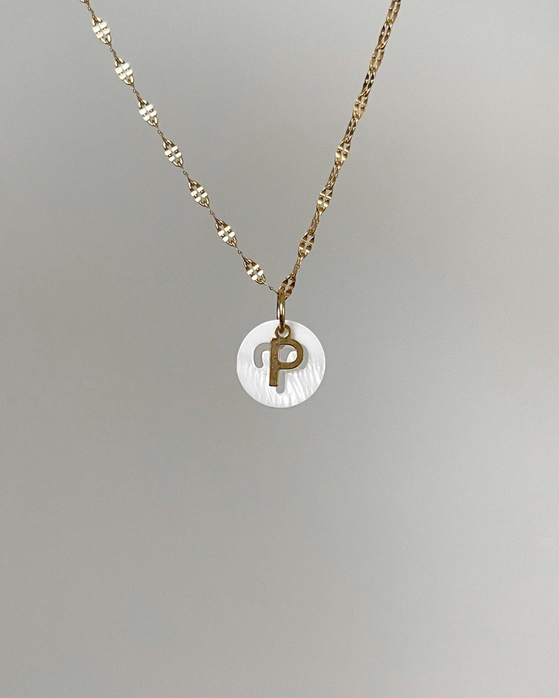 Weißer Charm mit ausgestanztem Sternzeichen Design an feiner Kette mit Buchstaben Charm.