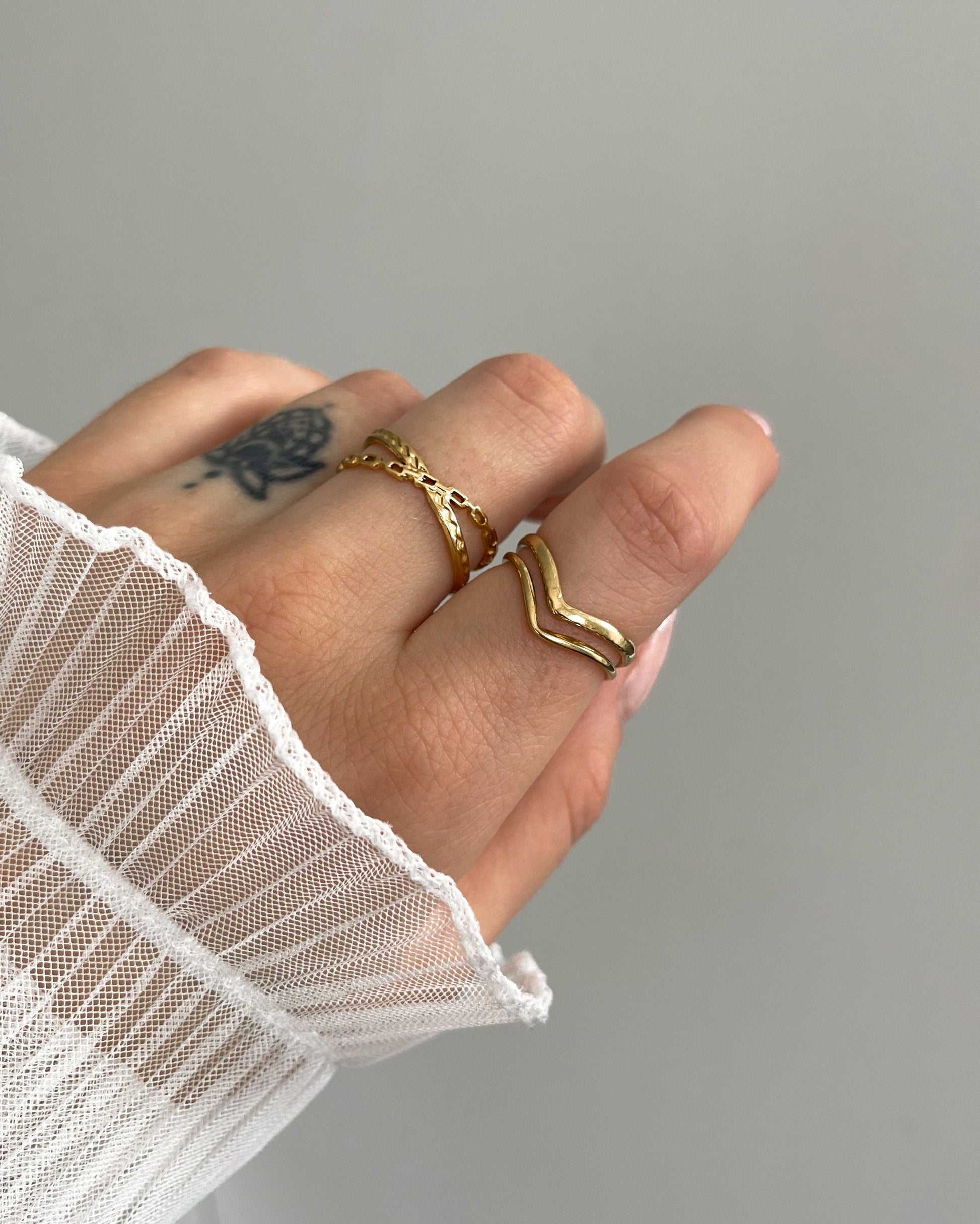 Wasserfester, verstellbarer Edelstahlring in gekreuztem Kettendesign, in gold getragen am Finger.