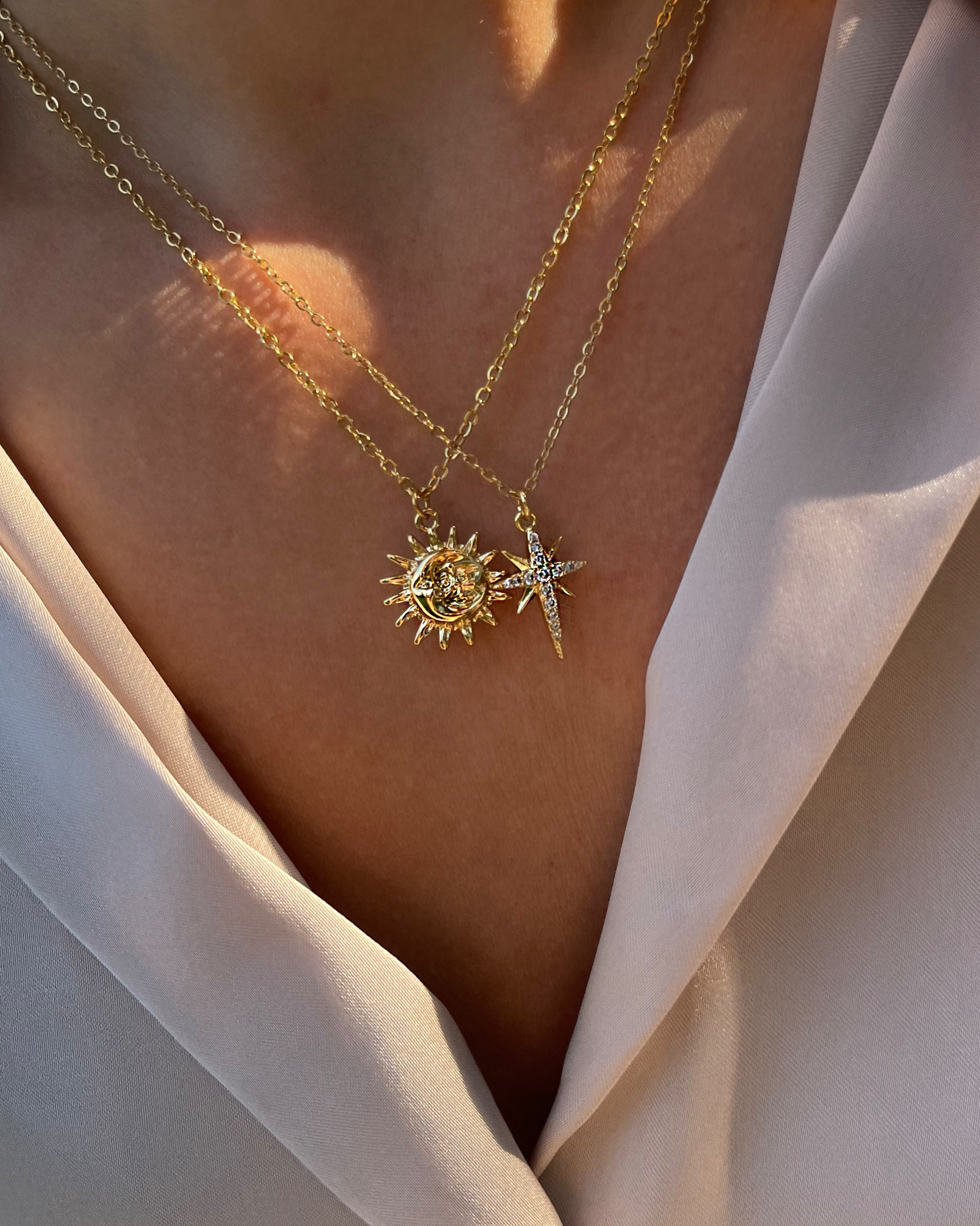 18k Vergoldete Edelstahlkette mit Mond & Sonnen Anhänger, getragen mit einer cremefarbener Bluse und kombiniert mit einer funkelnden Sternen Kette. Wasserfest, hypoallergen und verspieltes im Design.