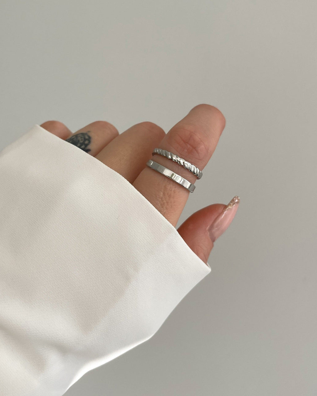 Doppellagiger, verstellbarer wasserfester Edelstahlring in silber, getragen am Finger.
