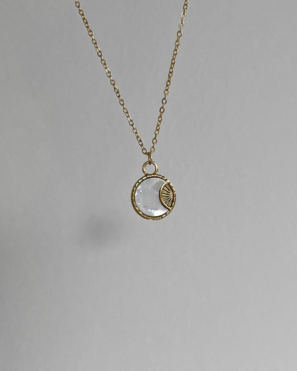 Goldene Halskette mit rundem schimmernden Plättchen.