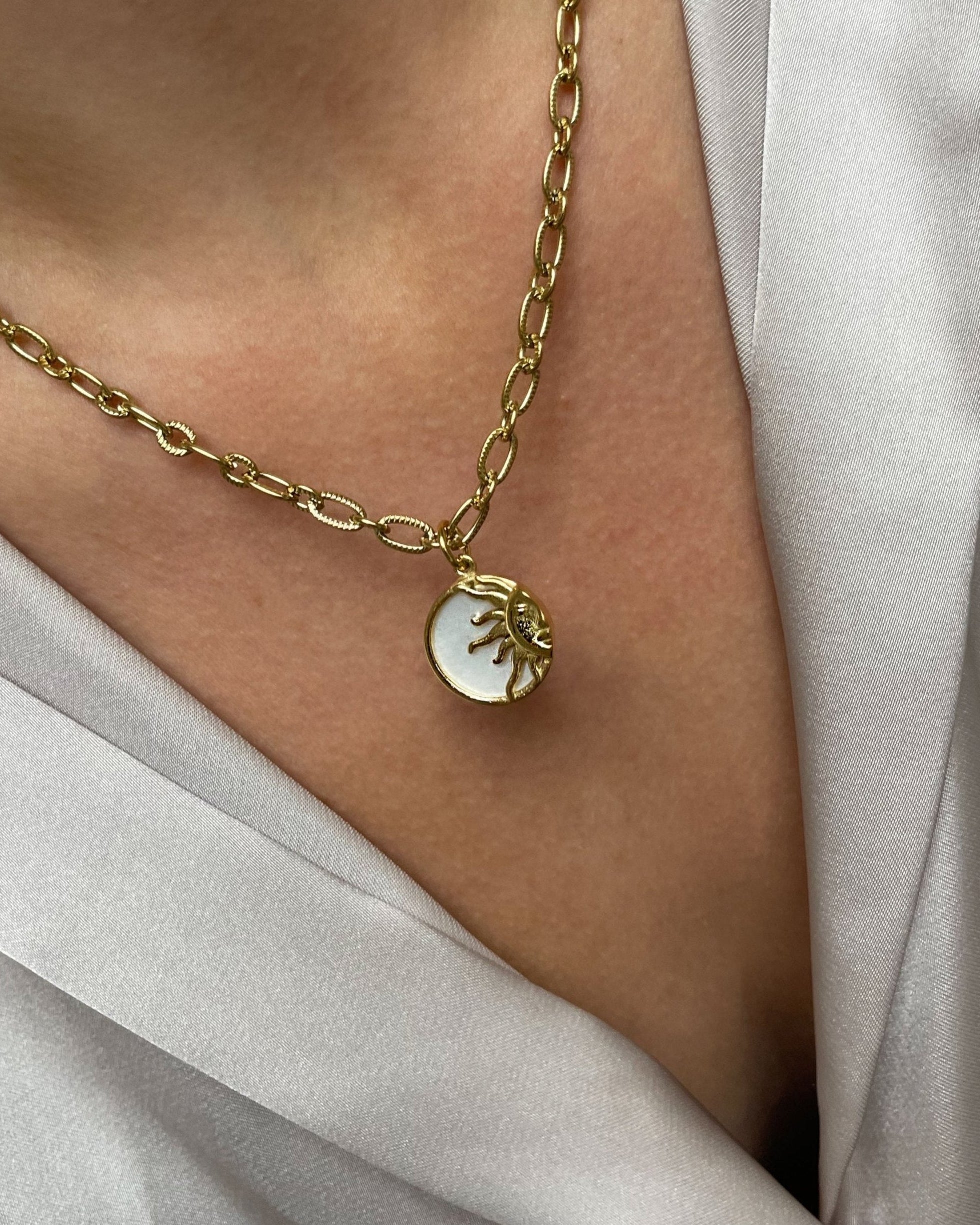 18k Vergoldete Edelstahl Kette mit Anhänger im Sonnen Design, getragen mit einer cremefarbenen Bluse. Wasserfest, hypoallergen und besonderes im Design.